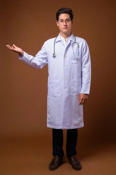 Молодий багатоетнічний красивий лікар на коричневому фоні — стокове фото