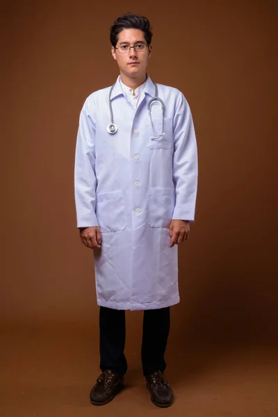 Młody Multi-etniczne przystojny lekarz przed brązowym tłem — Zdjęcie stockowe