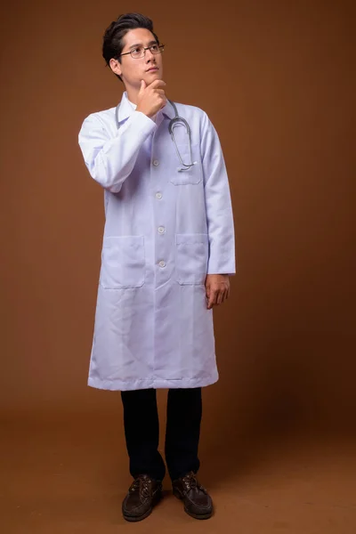 Młody Multi-etniczne przystojny lekarz przed brązowym tłem — Zdjęcie stockowe