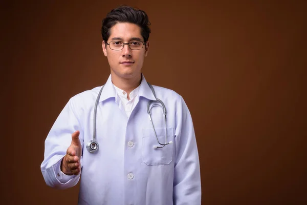 Fiatal többnemzetiségű csinos férfi orvos ellen, barna háttér — Stock Fotó