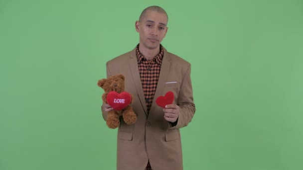 Грустный лысый многонациональный бизнесмен с плюшевым мишкой на День Святого Валентина — стоковое видео