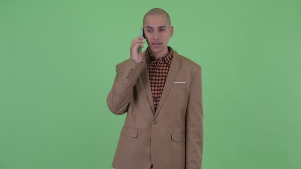 Zdůrazňoval holohlavý multietnický obchodník, který mluví po telefonu — Stock video