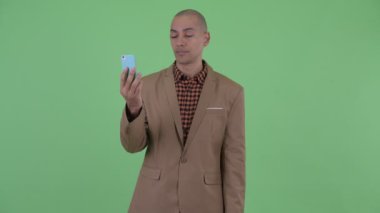 Ciddi kel çok etnik işadamı görüntülü arama ve telefon gösteren