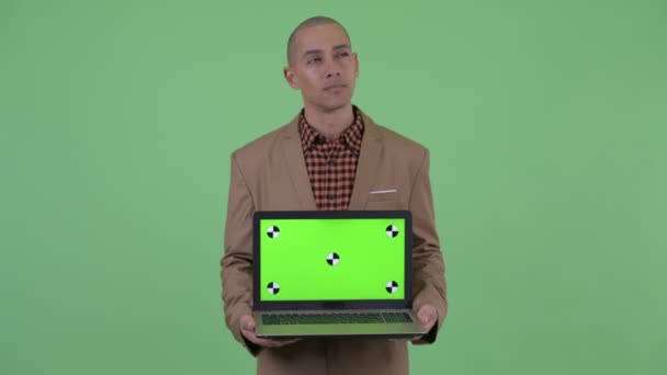 Serieuze kale multi etnische zakenman denken terwijl het tonen van laptop en klagen — Stockvideo