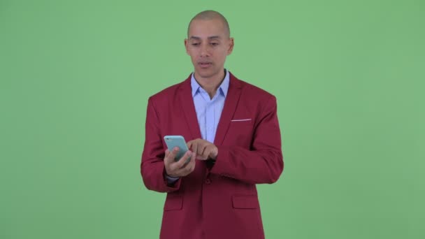 Stressed bald multi ethnic businessman using phone and getting bad news — Stock Video