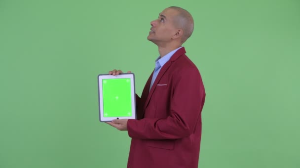 Счастливый лысый многонациональный бизнесмен думает, показывая цифровой планшет — стоковое видео
