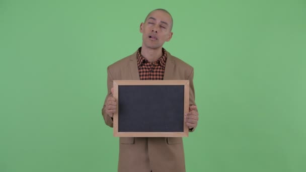 Vážný holohlavý multietnický obchodník přemýšlí a mluví, když drží tabuli — Stock video