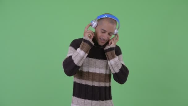 Happy Bald multi etnisk man lyssnar på musik redo för vintern — Stockvideo