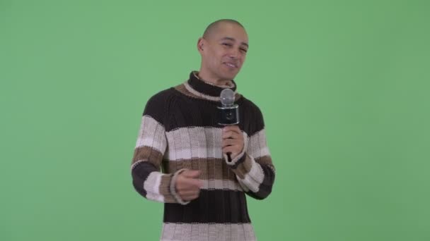 Happy bald multi ethnic man singing with microphone ready for winter — Stock Video