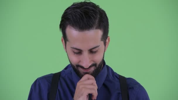Gesicht eines gestressten jungen bärtigen persischen Geschäftsmannes, der denkt und nach unten schaut — Stockvideo