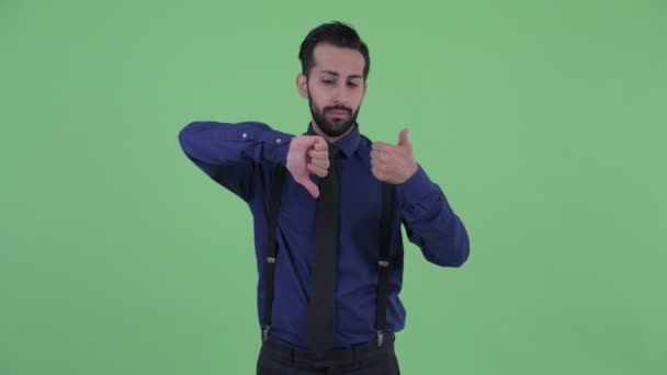 Плутати молодих бородатий Перська бізнесмен вибір між великими пальцями вгору і великі пальці вниз — стокове відео
