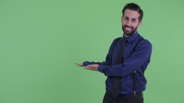 Щасливий молодий бородатий перський бізнесмен говорити, показуючи на спині — стокове відео