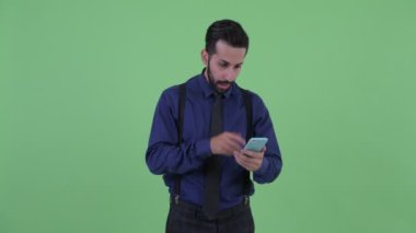Mutlu genç sakallı İranlı işadamı telefon kullanarak ve şaşırmış görünümlü