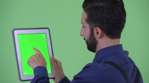 Vue arrière rapprochée de heureux jeune homme d'affaires perse barbu utilisant une tablette numérique — Video