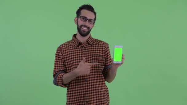 Feliz joven barbudo hipster persa hombre mostrando el teléfono y dando pulgares hacia arriba — Vídeos de Stock