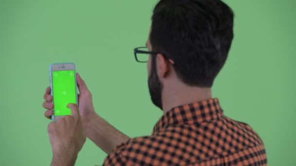 Kloseup pohled na šťastného mladého vousatého hipstera, který používá telefon — Stock video