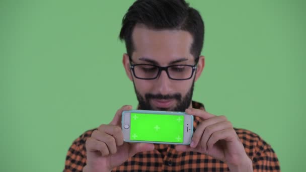 Обличчя щасливого молодого бородатого персидського хіпстера людини мислення під час показу телефону — стокове відео