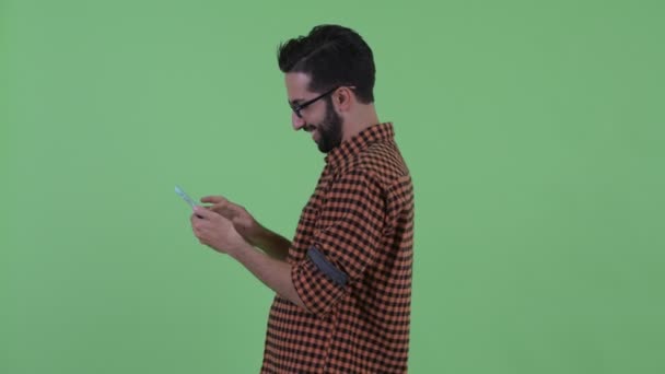 Vista de perfil de un joven hipster persa barbudo con teléfono quitado — Vídeos de Stock