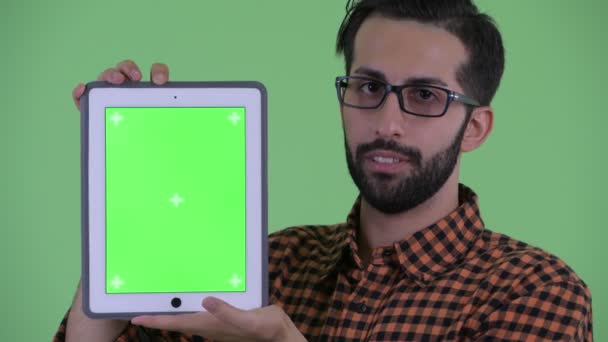 Cara de joven barbudo feliz hipster persa hombre hablando mientras muestra tableta digital — Vídeos de Stock