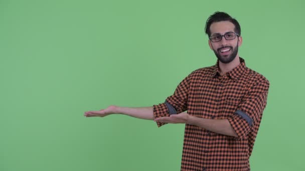 Feliz joven barbudo hombre hipster persa hablando mientras muestra algo — Vídeo de stock