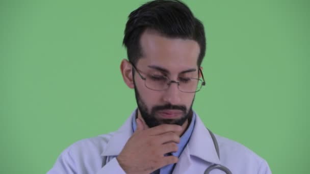 Rostro de estresado joven barbudo médico hombre persa pensando y mirando hacia abajo — Vídeo de stock