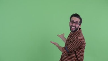 Mutlu genç sakallı Pers hipster adam arka gösteren ve şaşırmış bakıyor