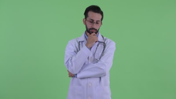 Gestresster junger bärtiger persischer Mann Arzt denkt und schaut nach unten — Stockvideo