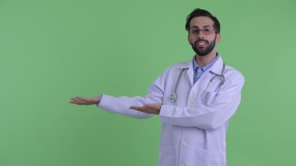 Boldog fiatal szakállas perzsa férfi orvos beszél és mutat valamit — Stock videók