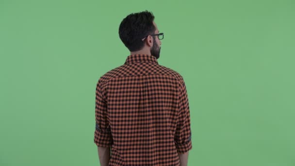 Bakifrån av unga skäggiga Persiska hipster man funderar och tittar runt — Stockvideo