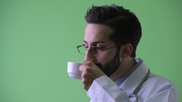 Vista del perfil de primer plano de feliz joven barbudo médico hombre persa beber café — Vídeos de Stock
