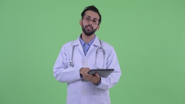 Jovem feliz barbudo persa homem médico falando ao usar tablet digital — Vídeo de Stock