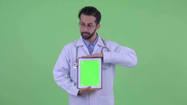 Šťastný mladý vousatý muž z Perského lékaře při zobrazování digitálního tabletu — Stock video