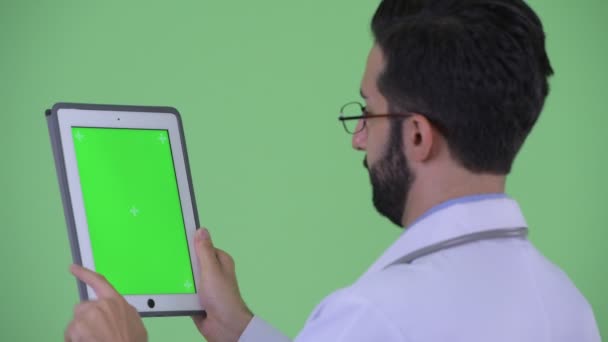 デジタルタブレットを使用して幸せな若いひげペルシャの男性医師のクローズアップリアビュー — ストック動画