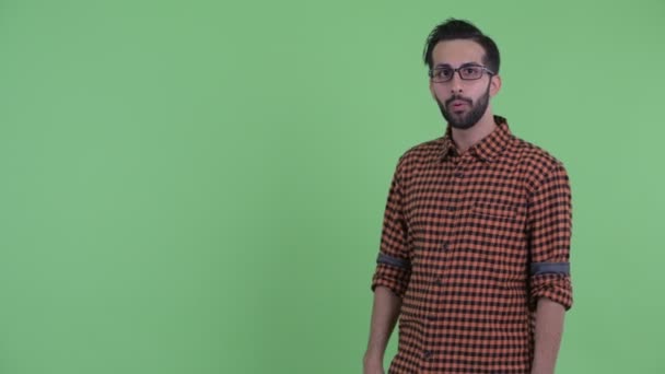 Happy Young bebaarde Perzische hipster man aanraken van iets en op zoek verrast — Stockvideo