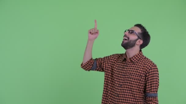 Feliz joven barbudo hipster persa hombre apuntando hacia arriba y mirando sorprendido — Vídeos de Stock