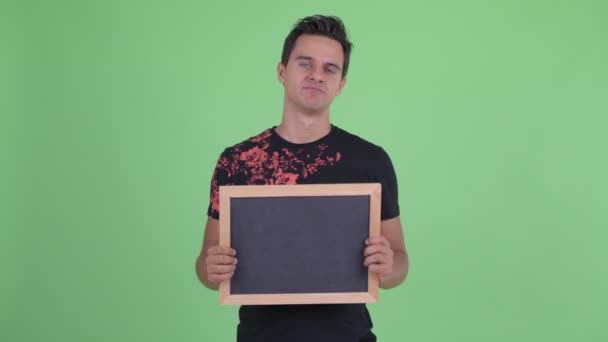 Beklemtoonde jonge man die Blackboard vasthoudt en slecht nieuws krijgt — Stockvideo