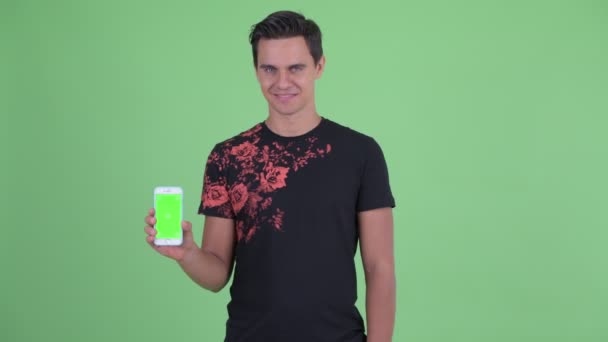 Boldog fiatal jóképű ember mutatja telefon és ad remek — Stock videók