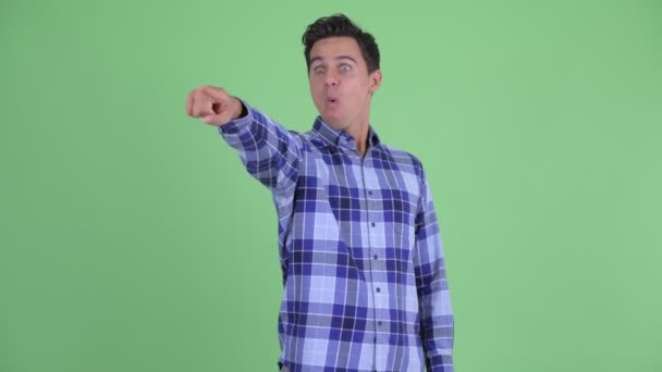 Gelukkig jonge knappe hipster man wijzend vinger en op zoek verrast — Stockvideo