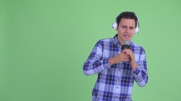 Heureux jeune homme hipster beau écoutant de la musique et chantant avec microphone — Video