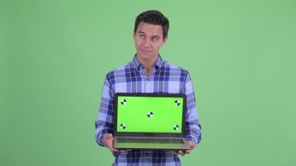 Feliz joven guapo hipster hombre pensando mientras que muestra el ordenador portátil — Vídeos de Stock