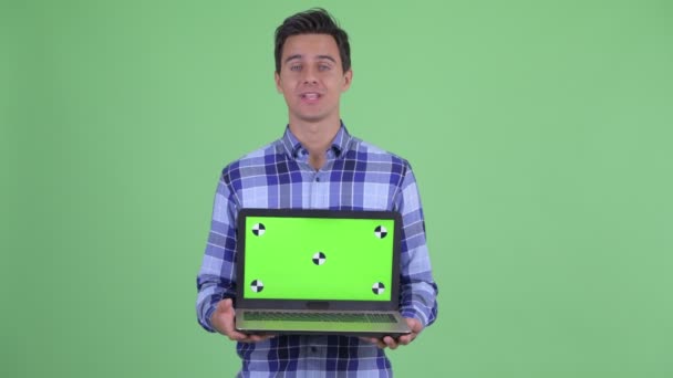 Šťastný mladý pohledný hipíček, který mluví, když zobrazuje laptop — Stock video