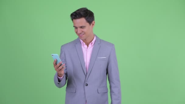 Szczęśliwy młody przystojny biznesmen myślenia przy użyciu telefonu — Wideo stockowe