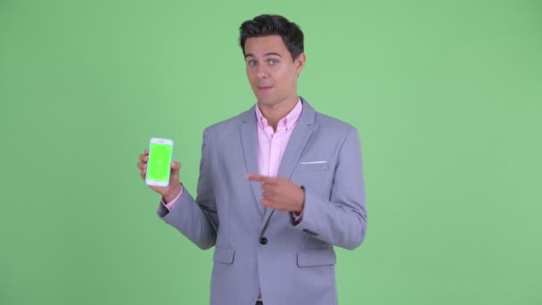 Šťastný mladý pohledný podnikatel ukazuje telefon a dává palec nahoru — Stock video