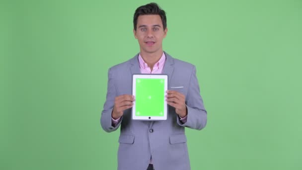 Boldog fiatal csinos üzletember beszél, miközben mutatja a digitális tabletta — Stock videók