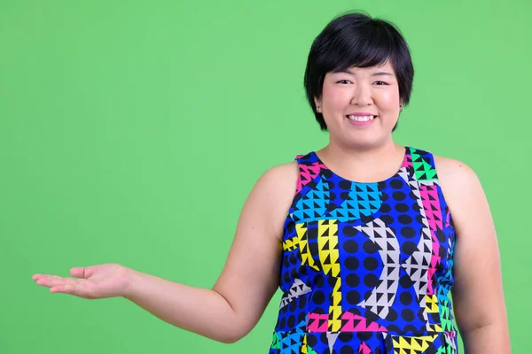 Giovane felice sovrappeso donna asiatica mostrando qualcosa di pronto per la festa — Foto Stock