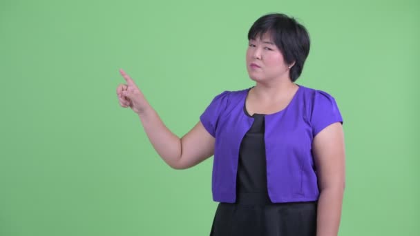 Счастливая молодая толстая азиатка трогает что-то и выглядит удивленной — стоковое видео