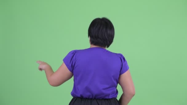 Hátulnézet a fiatal túlsúlyos ázsiai nő megható valamit — Stock videók