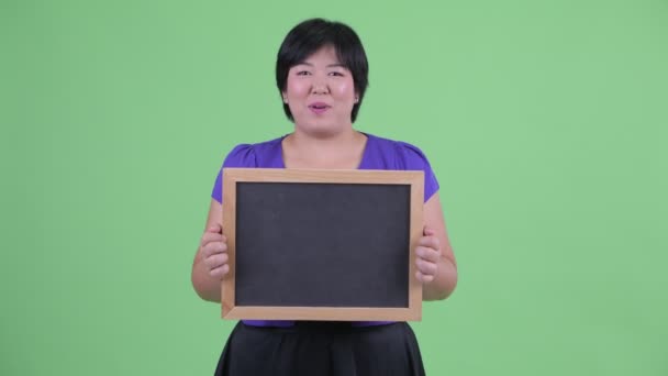 Щаслива молода надмірна вага азіатських жінка, що розмовляє при проведенні дошці — стокове відео