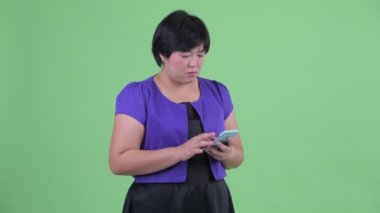 Mutlu genç kilolu Asyalı kadın telefon kullanarak ve taksi için arama