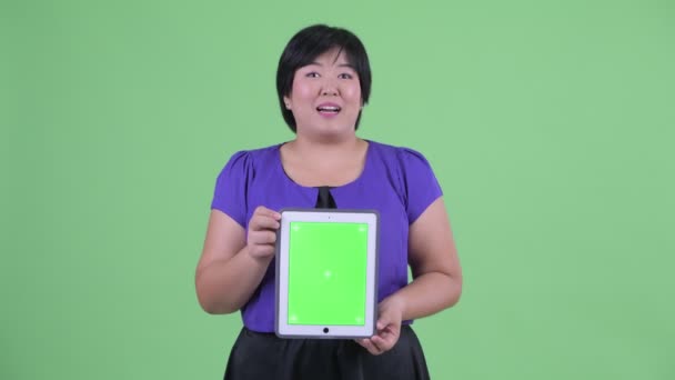 Heureux jeune femme asiatique en surpoids parler tout en montrant tablette numérique — Video